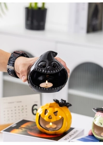 Detail of black ceramic ghost candle holder with a lit candle for Halloween decor
