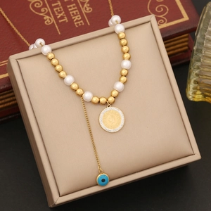 Detail of pearl necklace with coin pendant and evil eye charm on a vintage tray