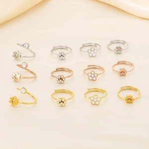 Flat lay view of twelve adjustable cat paw and flower rings in gold, silver, and rose gold