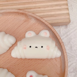 Cute white bunny ear croissant squishy toy made of soft resin on a wooden tray