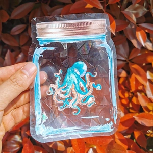 Holographic suncatcher sticker of a blue octopus in a jar with rainbow light effect