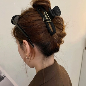 Detailed view of large black matte hair claw with golden triangle POWER lettering