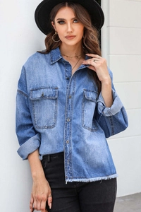 Detail of vintage blue denim shirt showing front pockets and frayed tassel hem design