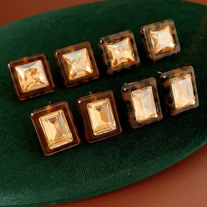 Detailed view of square resin earrings with amber crystals on green velvet padding