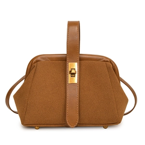 Detail of vintage brown shell bag showing smooth leather strap and matte suede texture