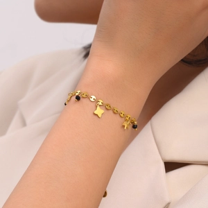Layered gold titanium bracelet with star charms and black beads on a woman's wrist