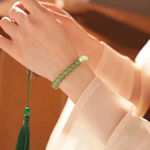Elegant green jasper bead bracelet with silk tassel shown on a woman's wrist