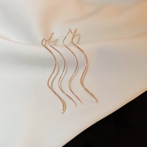 Detailed view of rose gold plated wavy threader earrings on elegant silk background