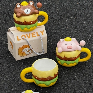 Cartoon burger ceramic mugs with bear and pig lids next to a lovely gift box