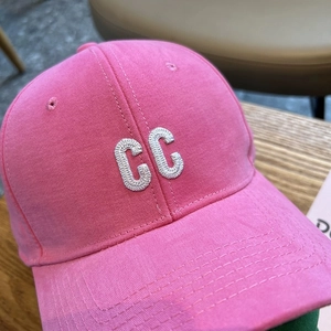 Close-up of pink baseball cap featuring white 3D letter CC embroidery and stitch details