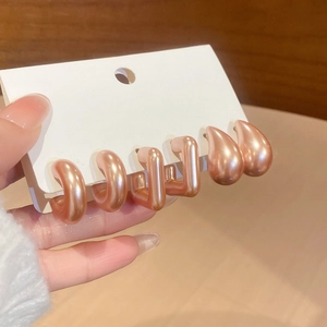 Detailed macro of three-pair acrylic earring set with pink pearl luster finish on card