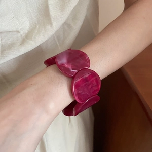 Close-up of red acrylic beaded bracelet with vintage marble texture worn on wrist