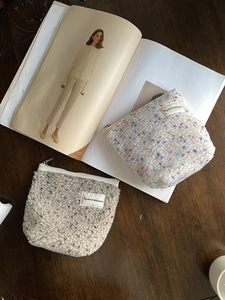 Vista piatta di pochette in lana di agnello peluche beige e grigio scuro su legno