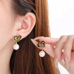 Detail of vintage heart-shaped knotted earrings with white pearl drops on a model