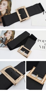 Detail of a wide black elastic waist belt with a large polished gold square buckle
