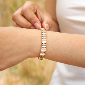 Close-up of a gold-plated link bracelet with pavé-set zircon stones worn on a wrist outdoors