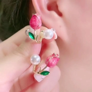 Macro detail of pink tulip earrings with enamel petals and white pearl pendant