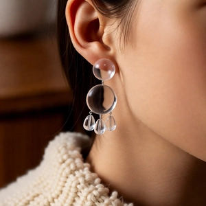 Close-up of clear resin drop earrings with circular beads and tiny water-drop charms