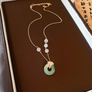 Détail du collier doré avec feuille de ginkgo et pendentif en jade vert en boîte