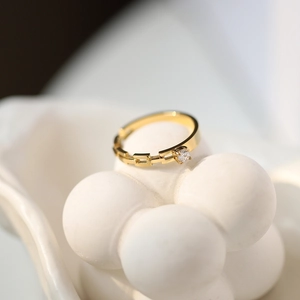 Macro shot of 18K gold plated chain ring with a clear zircon on a white shell stand