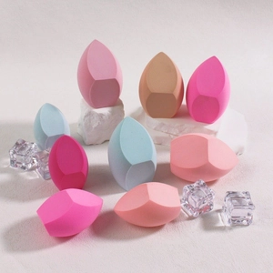 Set of 9 colorful jumbo makeup sponges in teardrop and cut shapes on white marble background