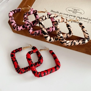 Detailed macro view of retro leopard print textured square hoop earrings in three color schemes