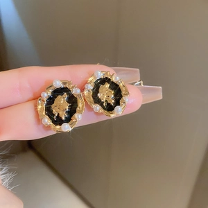 Detailed macro view of French vintage pearl earrings with black enamel and golden motifs