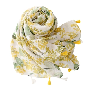 Floral cotton scarf with yellow leaf prints and tassels, displayed in a spiral fold style