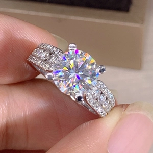 Macro detail of a classic four-prong solitaire moissanite ring with luxury pavé side stones