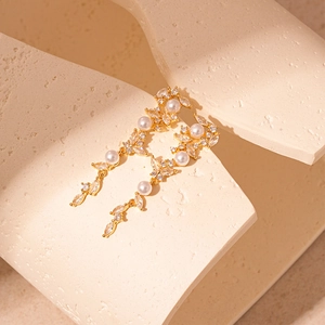 Detail of elegant gold tassel earrings with pearls and marquise cut cubic zirconia