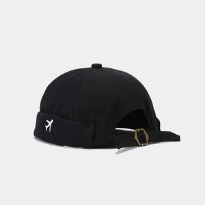 Vue détaillée du bonnet Miki noir avec broderie avion et boucle en métal bronze