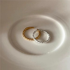 Detailed view of gold and silver S925 sterling silver twisted rope rings in a ceramic tray