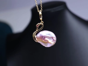 Vue macro d'un pendentif cygne avec perle baroque naturelle et détails plaqués en or