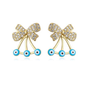 Macro shot of gold plated bow earrings with zircon stones and blue evil eye charms