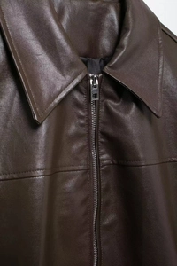 Close-up of dark brown faux leather aviator jacket featuring collar and metal zipper detail