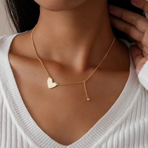 Detail of a vintage wrinkled gold heart pendant necklace on an elegant ribbed fabric