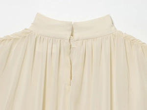 Close-up of pleated high collar on a cream chiffon blouse with back slit detail