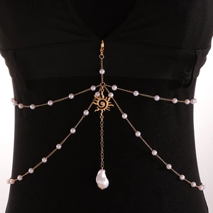 Detail of gold multilayer body chain featuring white pearls and sun pendant with baroque pearl