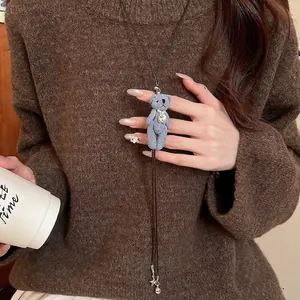Long collier de pull avec pendentif ours en denim bleu et perles sur un pull en maille marron