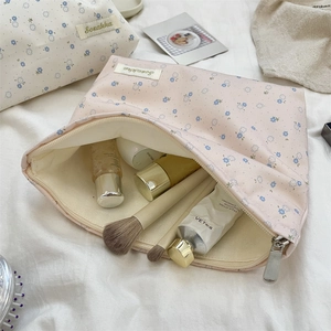 Pink floral canvas makeup bag with zipper open showing brushes and skincare bottles