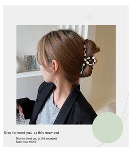 Detail of large checkerboard hair claw clip holding hair bun in a modern minimalist setting