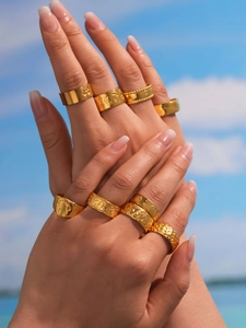 Detailed close-up of a stack of gold-plated stainless steel rings with Y2K textured designs