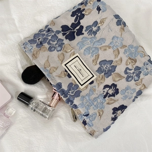 Détail de la broderie florale sur une trousse de maquillage avec fermeture éclair en métal