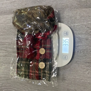 Close-up of a plaid Christmas wine bottle cover with faux fur collar and bow detail