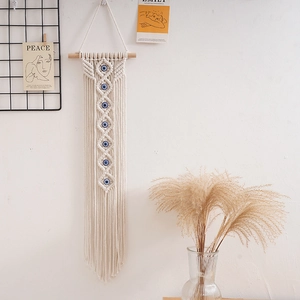 Detail of hand-woven cotton tapestry with blue evil eye beads and decorative tassels