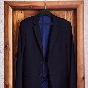 Giacca da uomo blu navy su gruccia in legno nero con due bottoni e rever classico