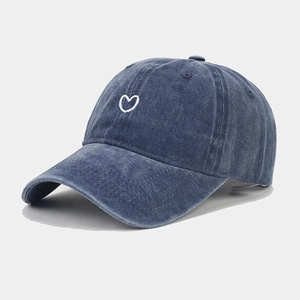 Detailed close-up of white heart embroidery on a vintage washed navy baseball cap