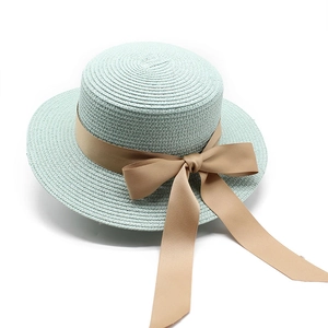 Dettaglio di un cappello paglia verde menta con nastro beige e fiocco laterale decorativo