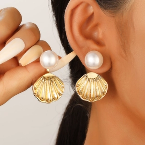 Detailed view of elegant shell pearl earrings featuring golden metallic scallop drop charms