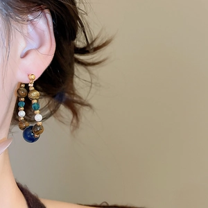 Detail of bohemian drop earring with tiger eye, blue crystal and white pearl on model